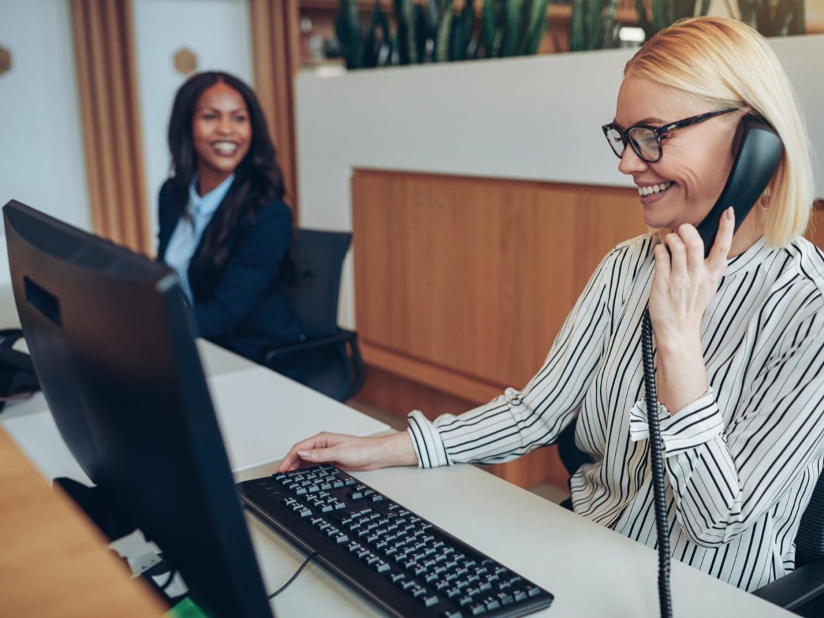 Two receptionists working together at an office front desk