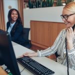 Two receptionists working together at an office front desk