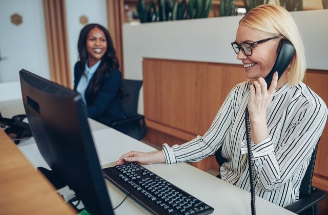 Two receptionists working together at an office front desk