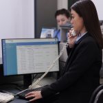 Receptionist using a telephone and computer at a reception desk